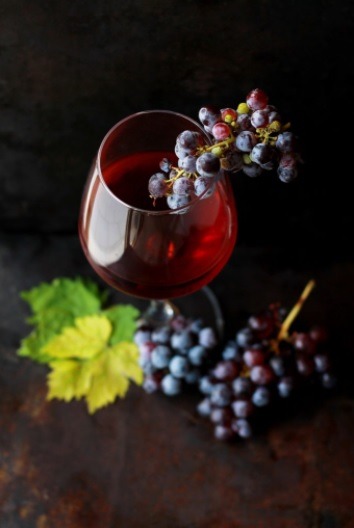 Rotwein in einem Glas. Daneben sind Weintrauben
